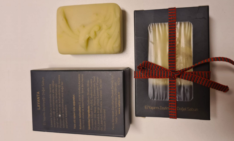 Parıltı Organik Sabunları ürünlerinin doğal bitkiler ve aromalarla sunulduğu dekoratif tanıtım sahnesi.